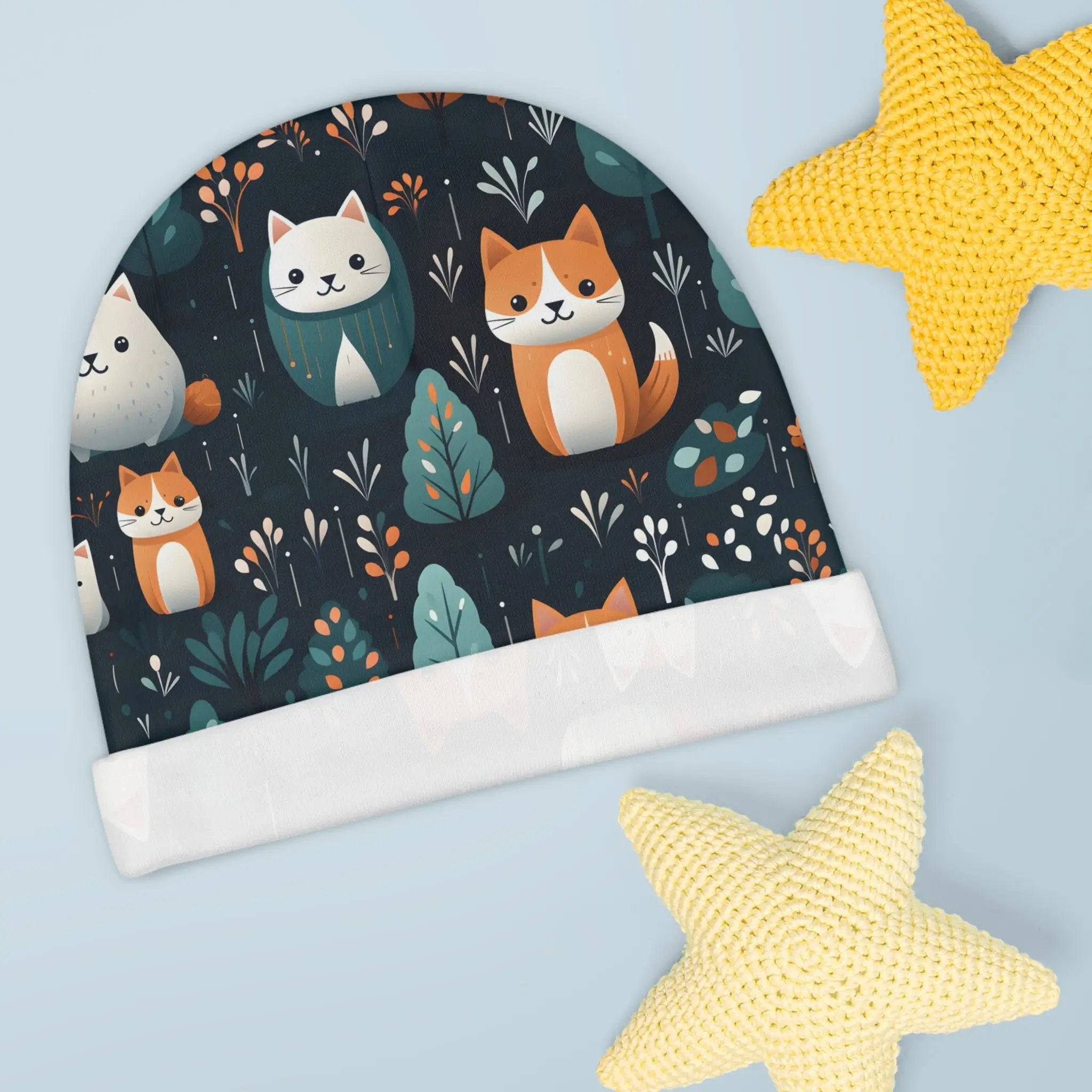 Baby Beanie | a knitted hat with cats on it next to a starfish