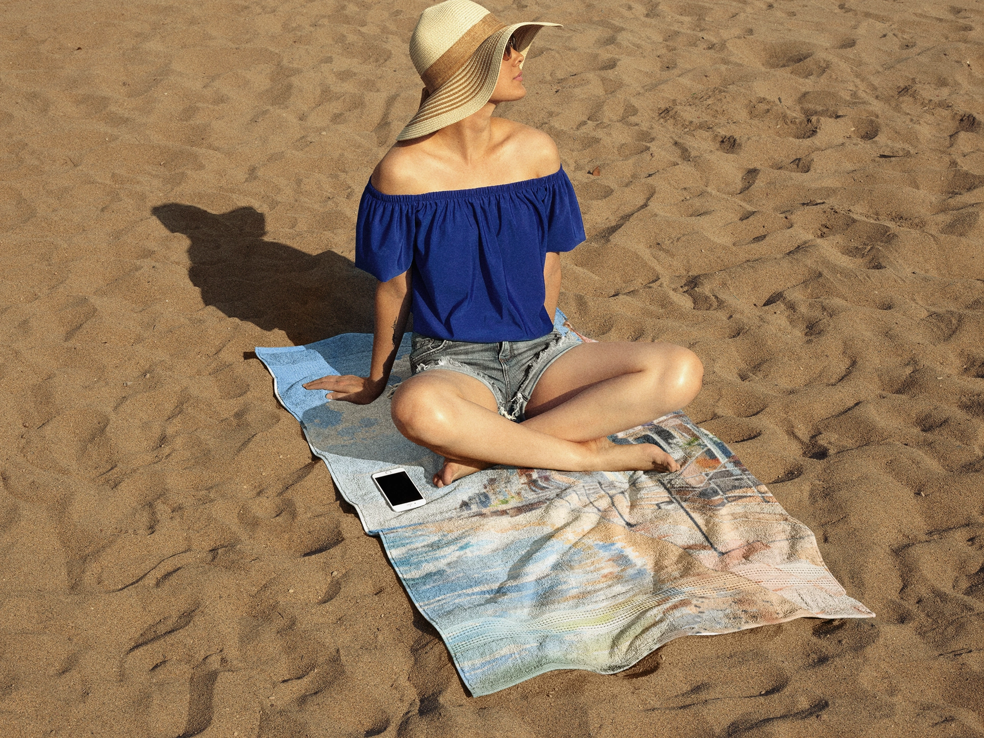 Best bath towel | a woman sitting on top of a towel on top of a beach