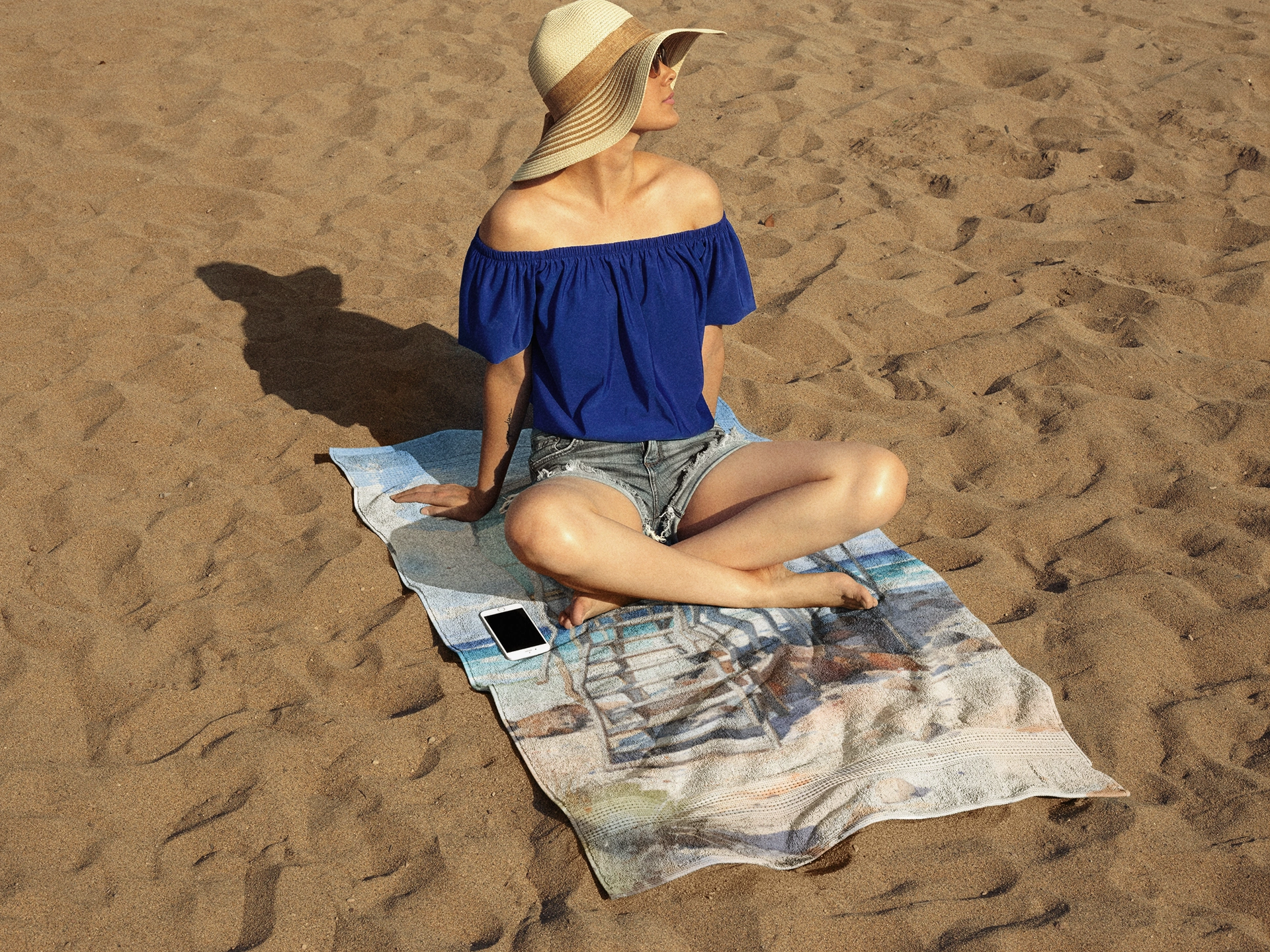 Best bath towel | a woman sitting on top of a towel on top of a beach