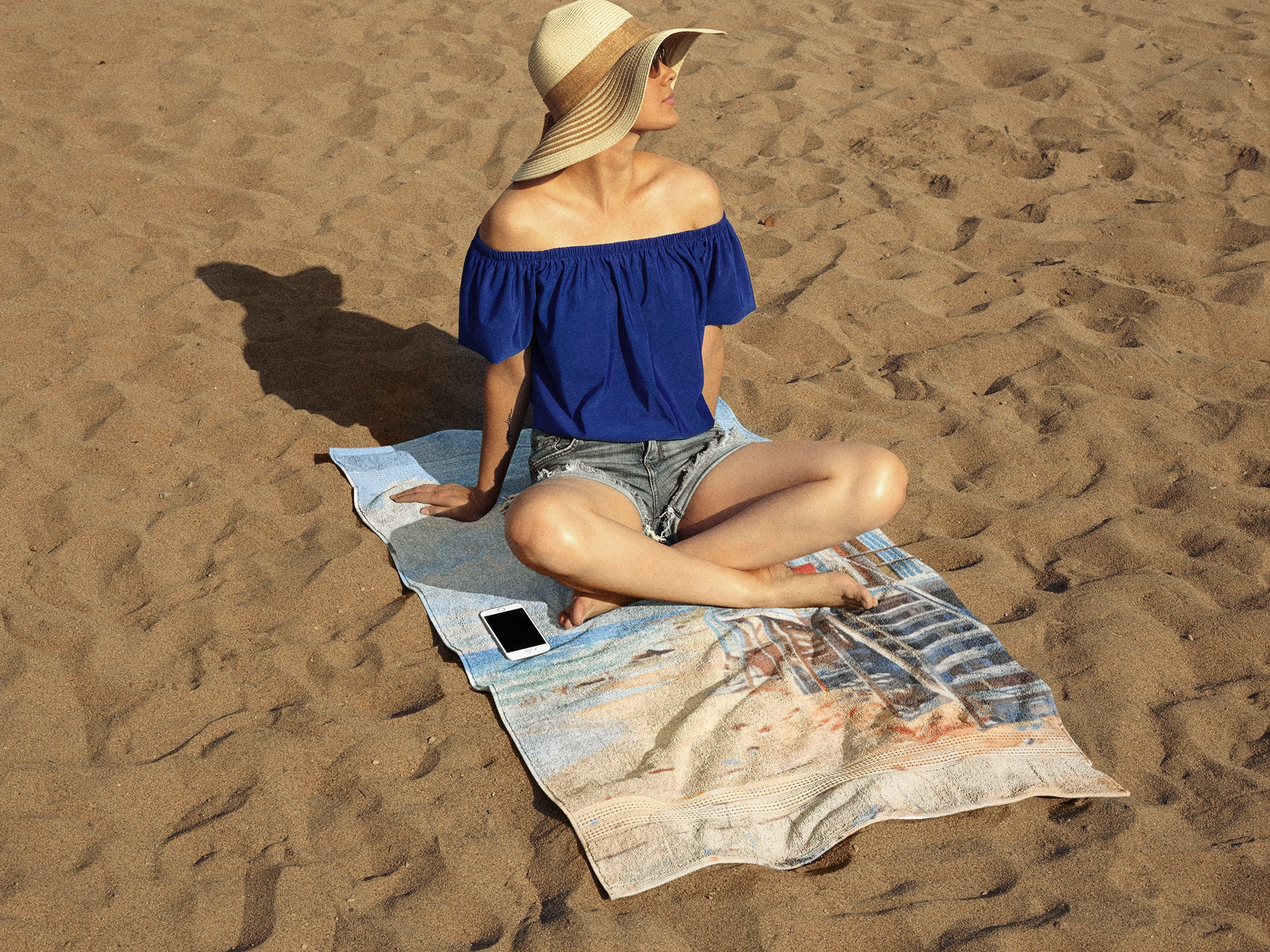 Best bath towel | a woman sitting on top of a towel on top of a beach